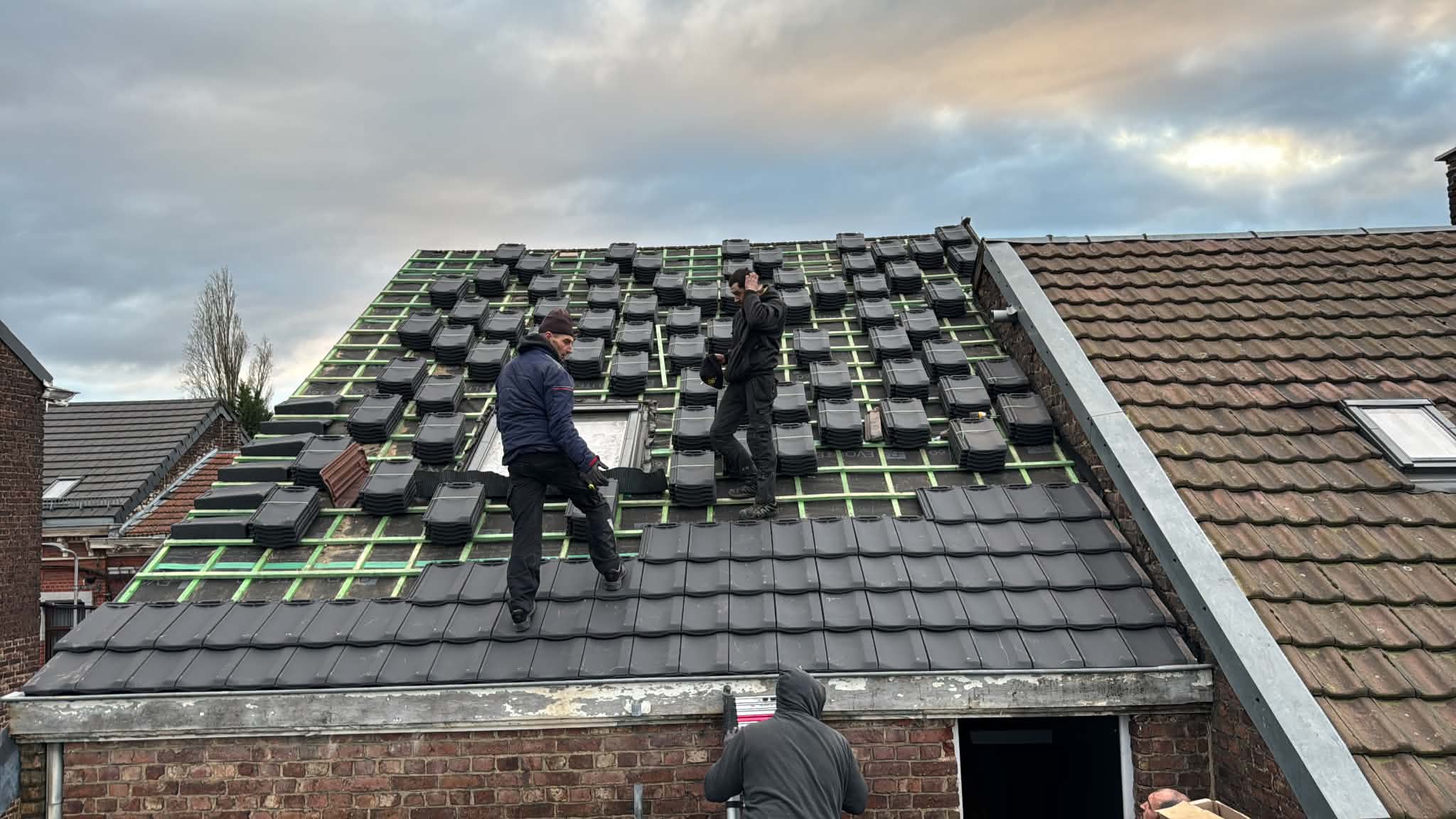 Couvreurs posant des tuiles sur une toiture en rénovation