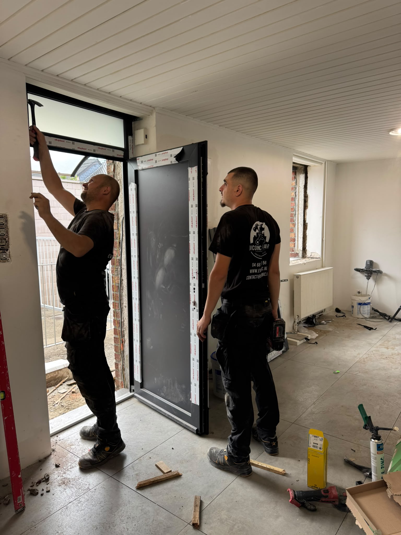 Deux ouvriers EVCONIC posant une porte d’entrée foncée